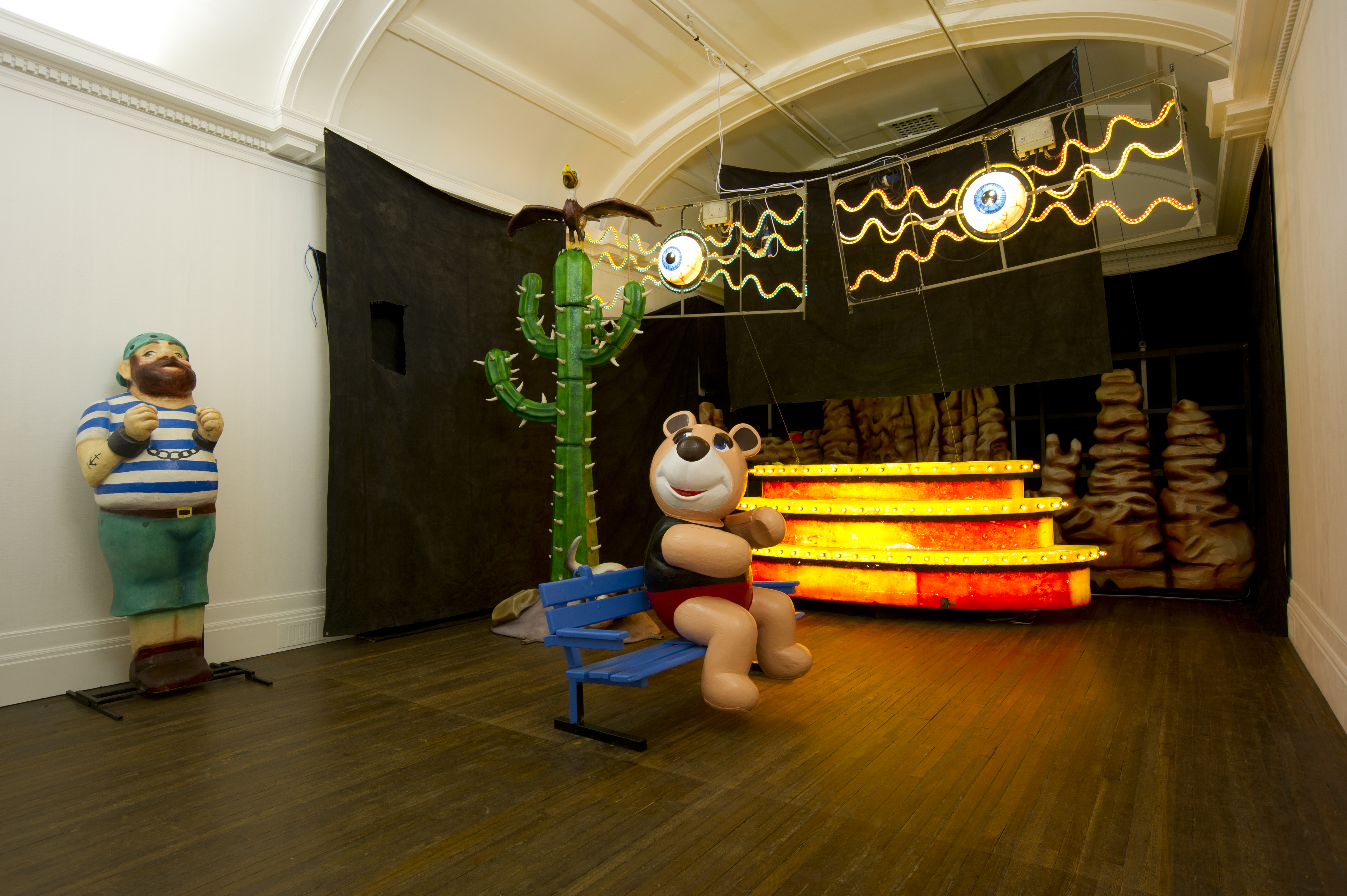 Various items from The Blackpool Illuminations. Objects include pirate, cactus, eyes with lines radiating from them, and large teddy bear on bench. The objects were included in the exhibition ON: A Re-Imagining Of Blackpool Illuminations by Brian Griffith.