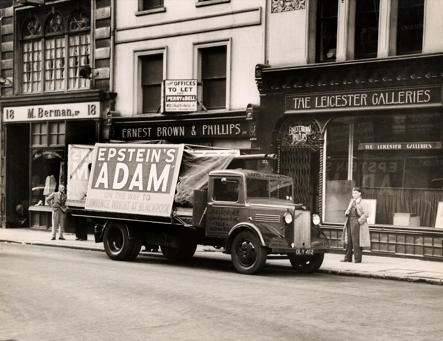 Historic photograph in black and white of Blackpool shops with truck displaying advertisement for the display of controversial sculpture Adam, by artist Jacob Epstein.