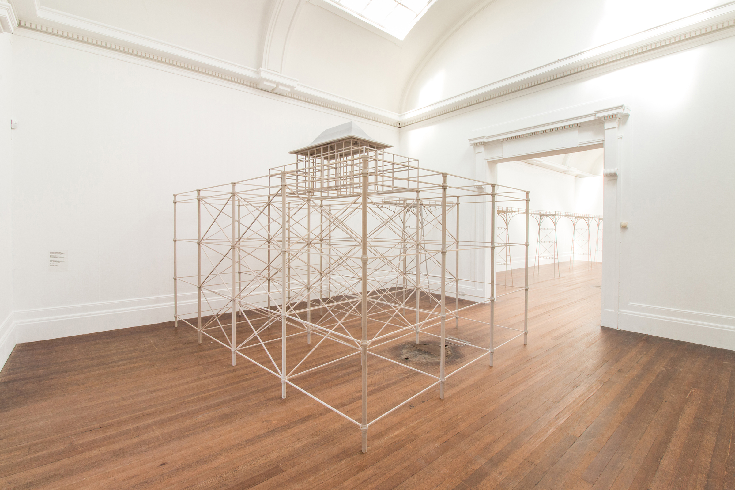 Large wooden pier. The pier created by artist Roy Voss is constructed in pale wooden dowelling.The pier crosses from one gallery into the next by the appearance of it passing through adjoining wall. Included in the exhibition Roy Voss: The Way Things Are.